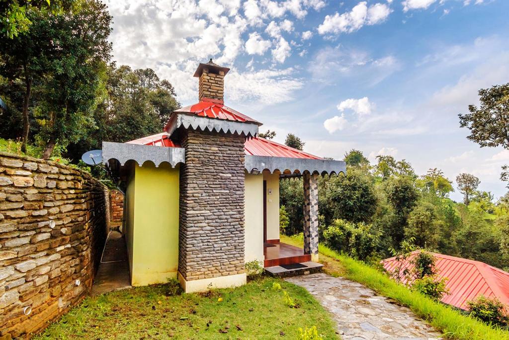 a small house with a chimney on top of a wall at Himalaya Darshan Resort in Kausani