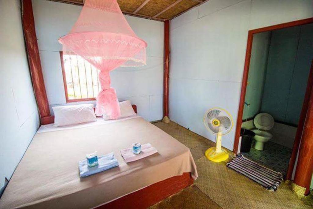 una camera con letto a baldacchino rosa e ventilatore di Ning Ning Bungalow a Don Det