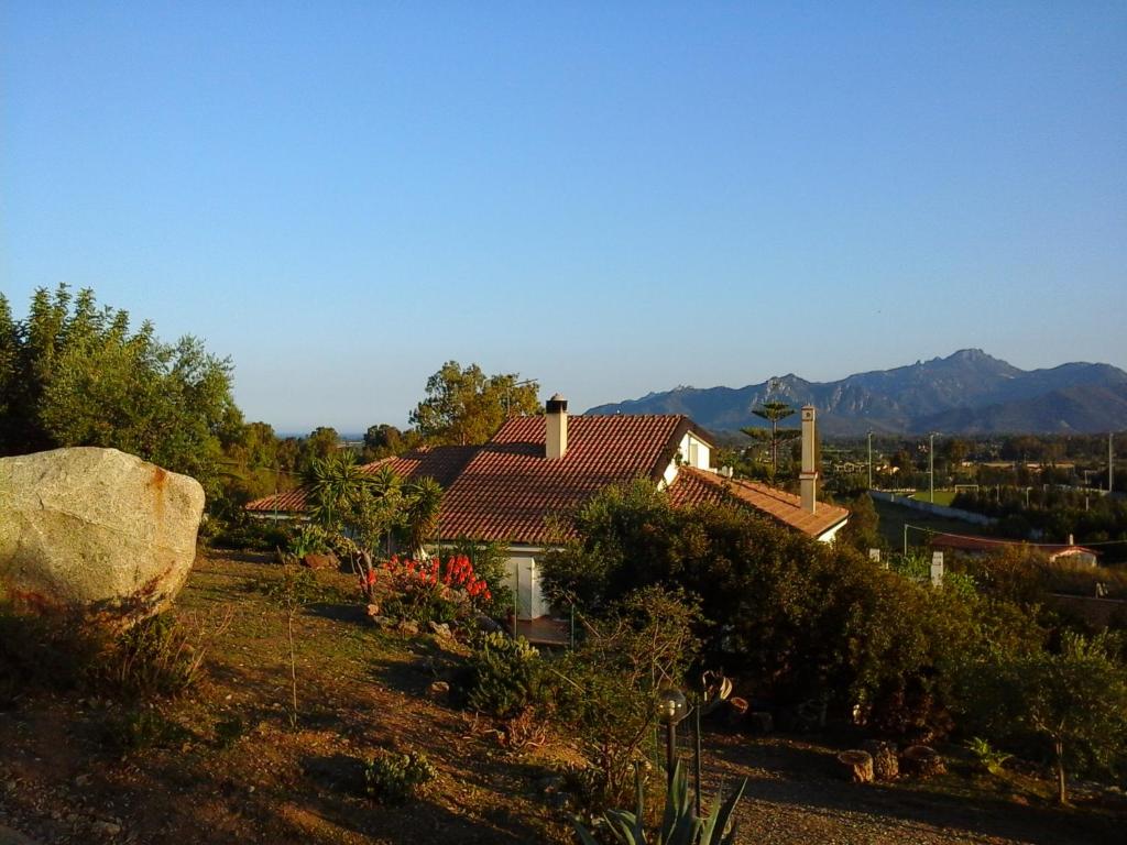 ein Haus in einem Garten mit Bergen im Hintergrund in der Unterkunft Agriturismo Chiai Francesco in Bari Sardo