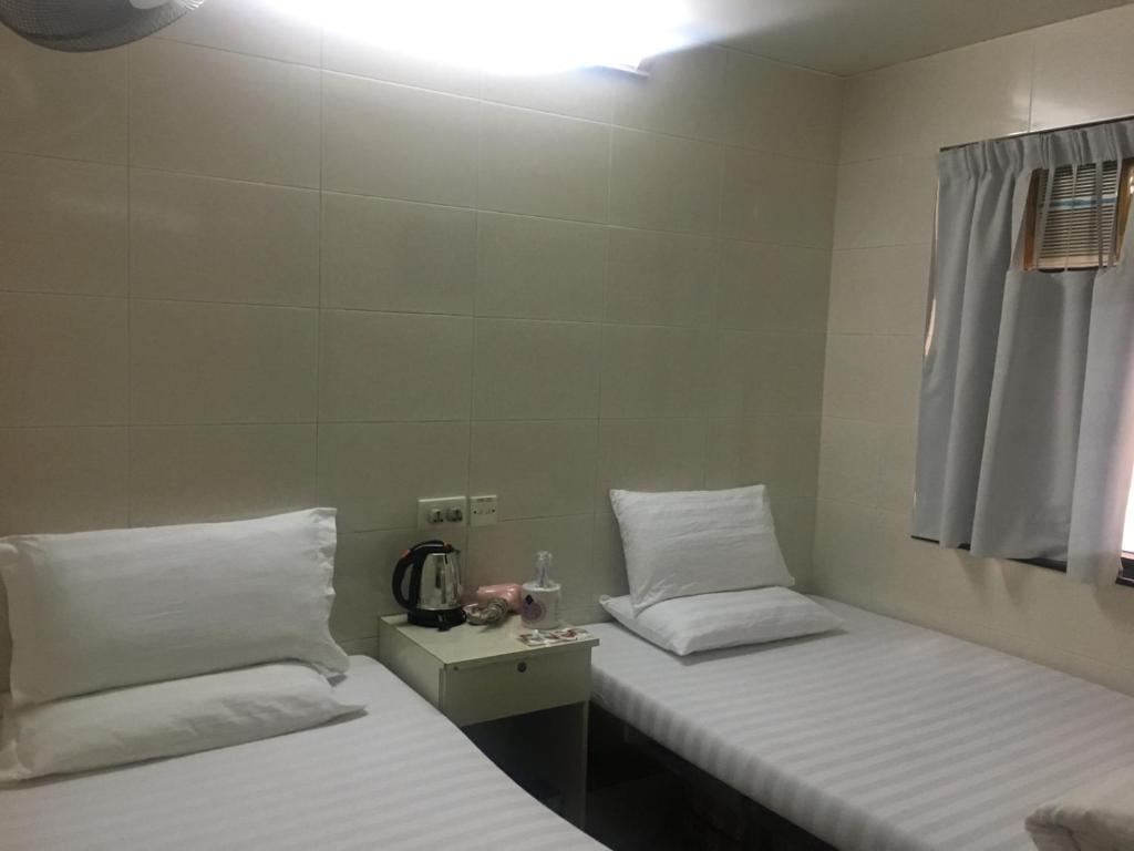 two beds in a room with white pillows at Unique Hostel in Hong Kong