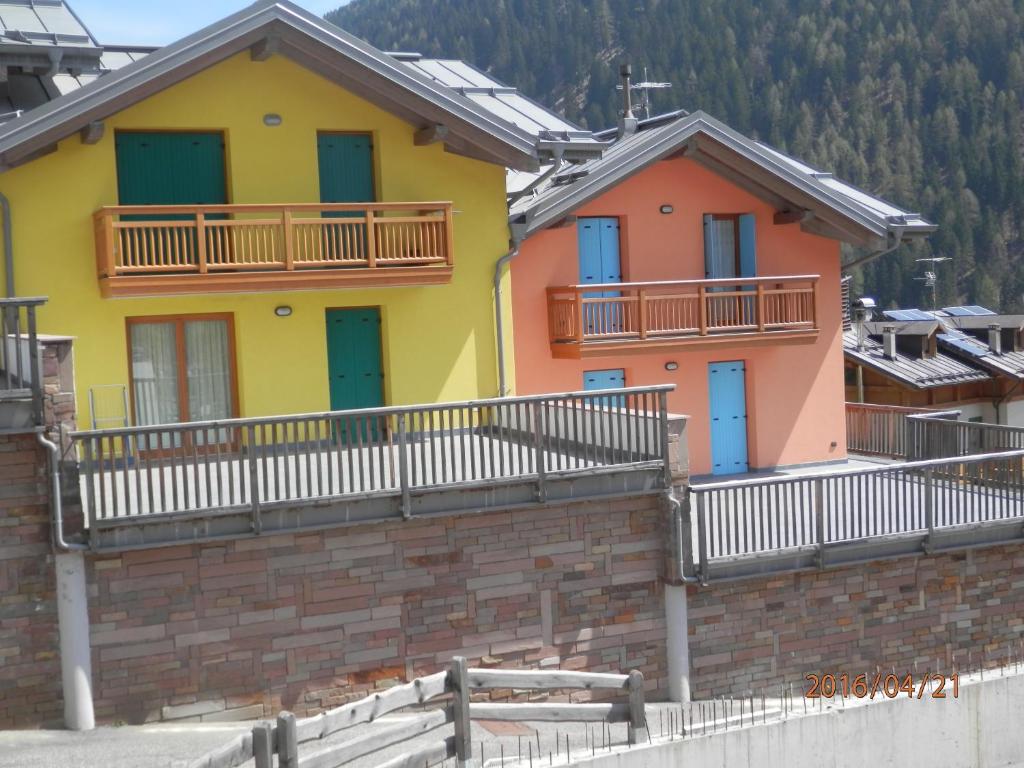 een rij huizen met kleurrijke deuren en balkons bij Appartamenti Presanella in Vermiglio