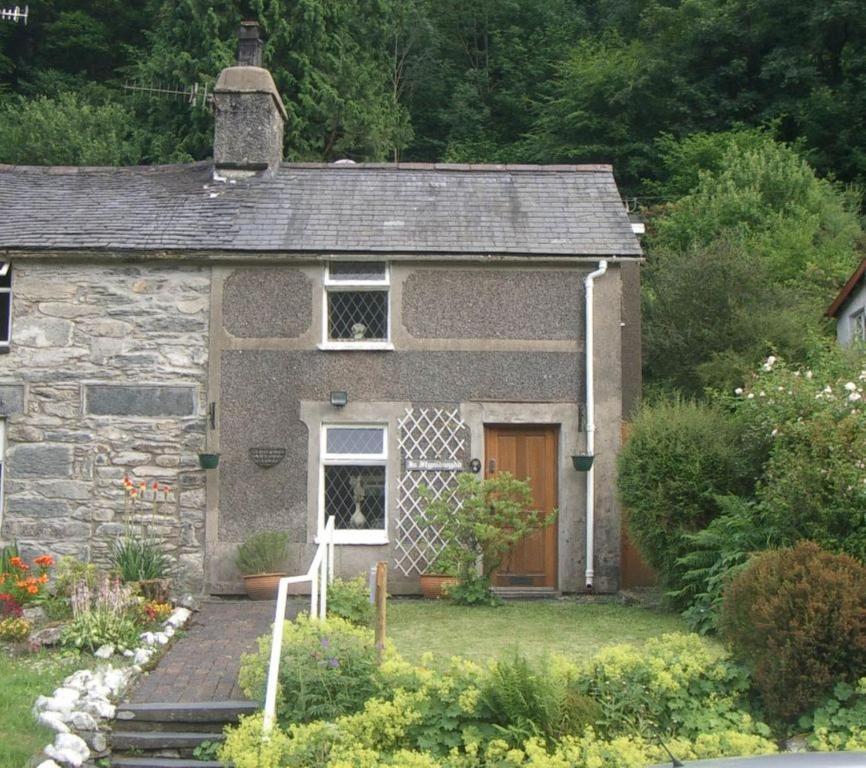 a small stone house with a door in a garden at Llugwy Cottage in Betws-y-coed