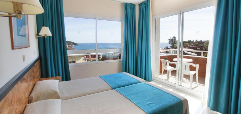 リョレート・デ・マルにあるHotel Gran Garbi Mar & AquaSplashのベッドと大きな窓が備わるホテルルームです。