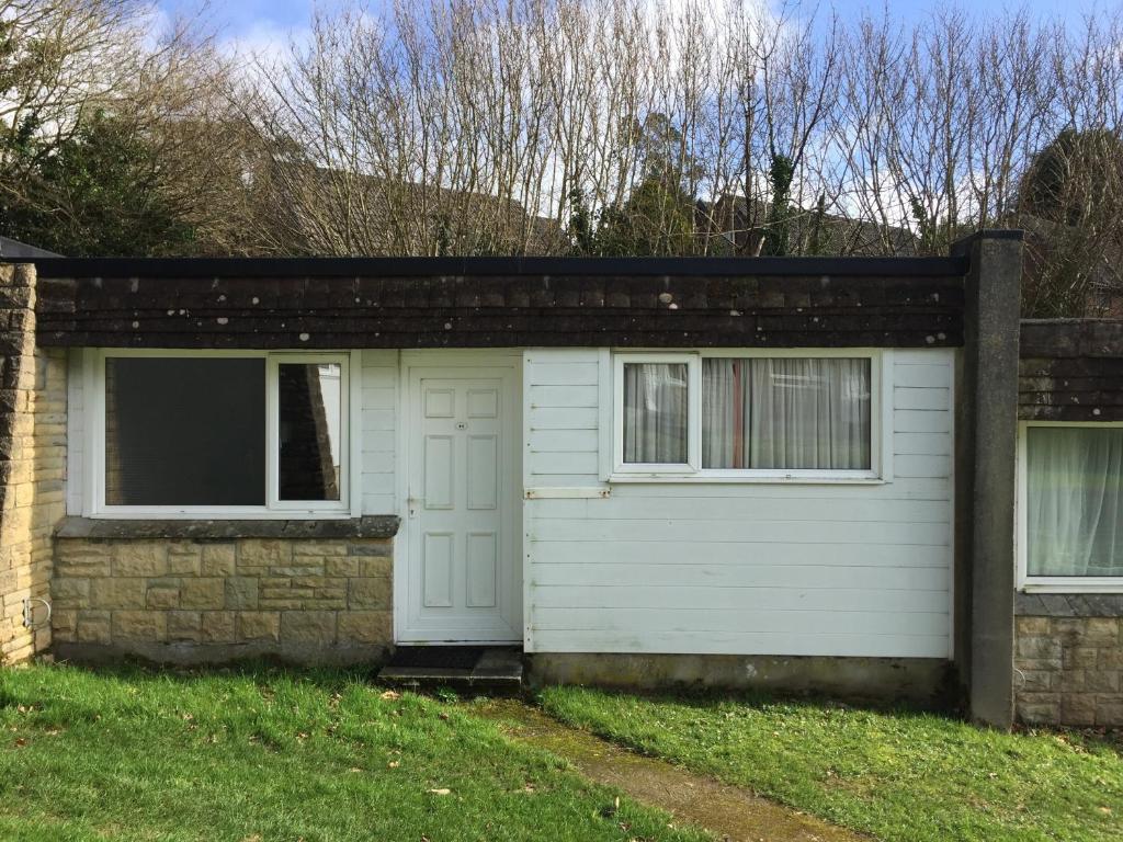 a white garage with a window and a brick wall at Villa 44 in Camelford