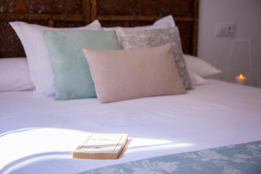 a book sitting on top of a bed with pillows at Lukanda Arenal in Seville