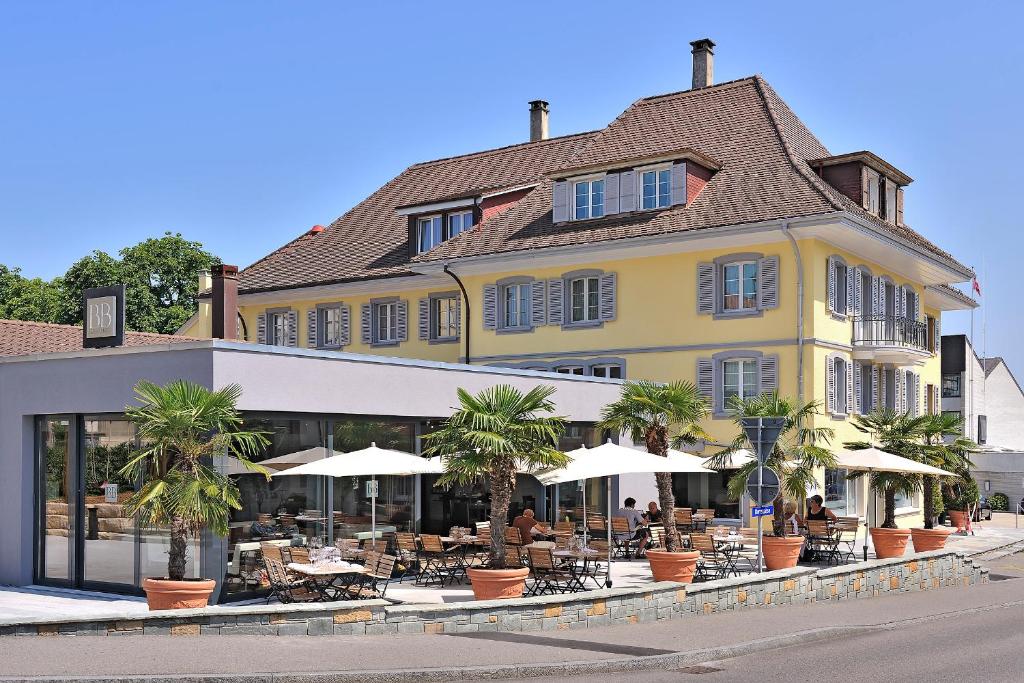 a yellow building with tables and umbrellas on a street at Hotel Murten in Murten