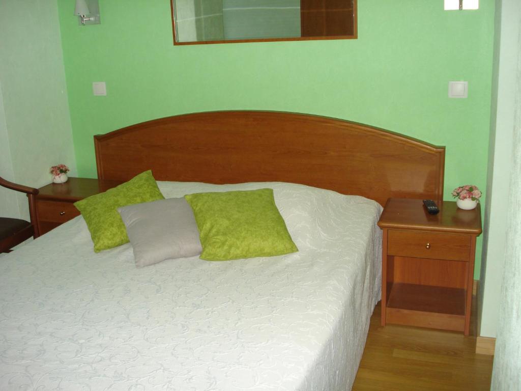 Una cama con dos almohadas verdes encima. en Chambres d'hôtes la Chaumière, en Arcy-sur-Cure