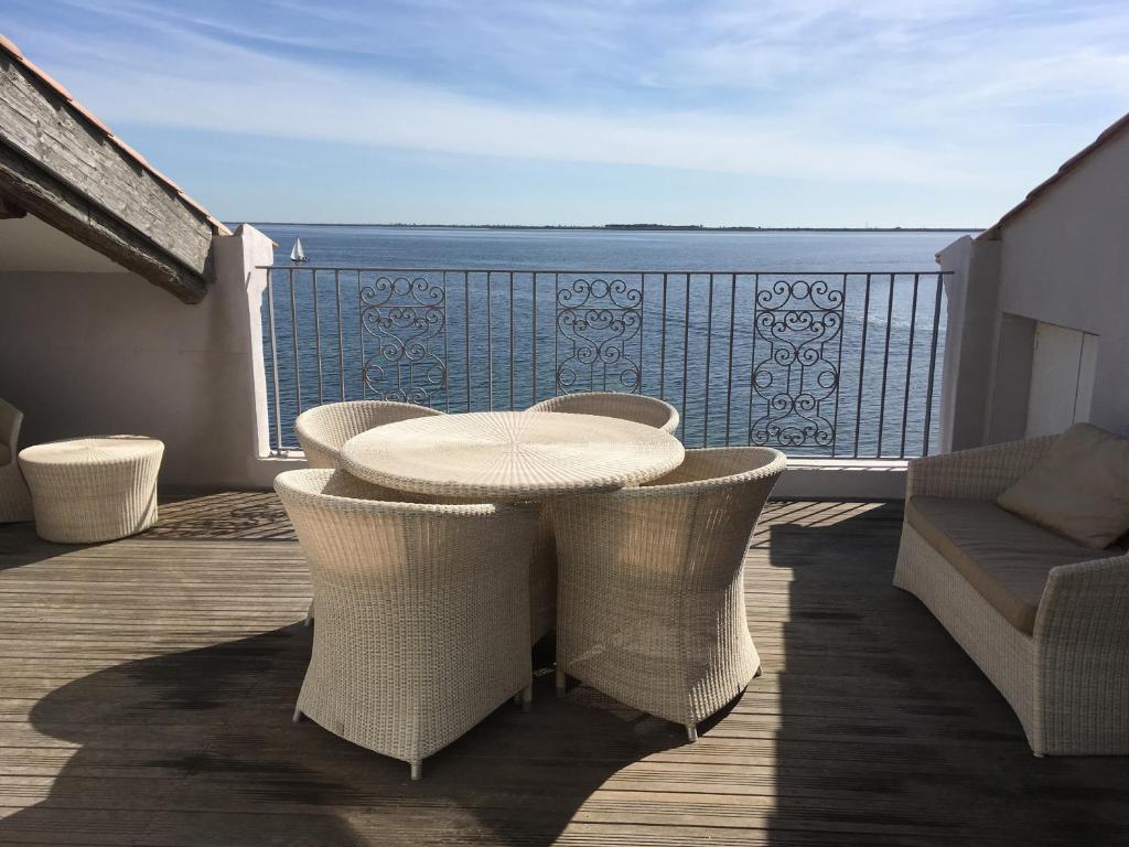 een tafel en stoelen op een balkon met uitzicht op de oceaan bij Port rive gauche Iona in Marseillan