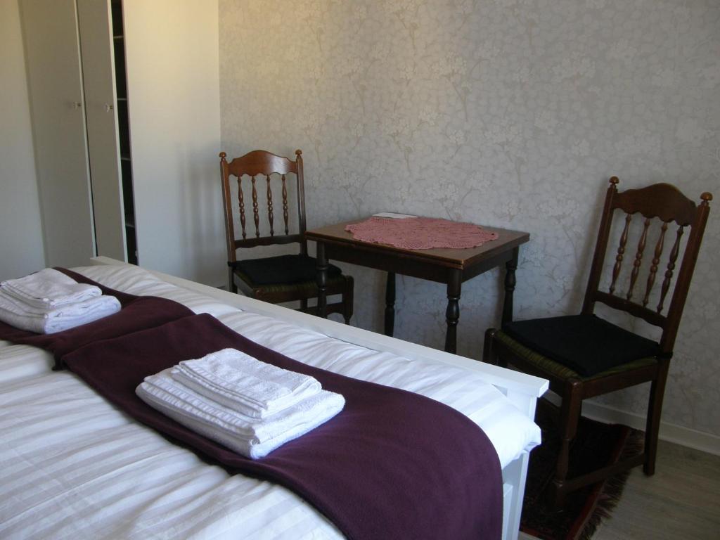 a bedroom with a bed and two chairs and a table at Monicas Rumsuthyrning in Borgholm