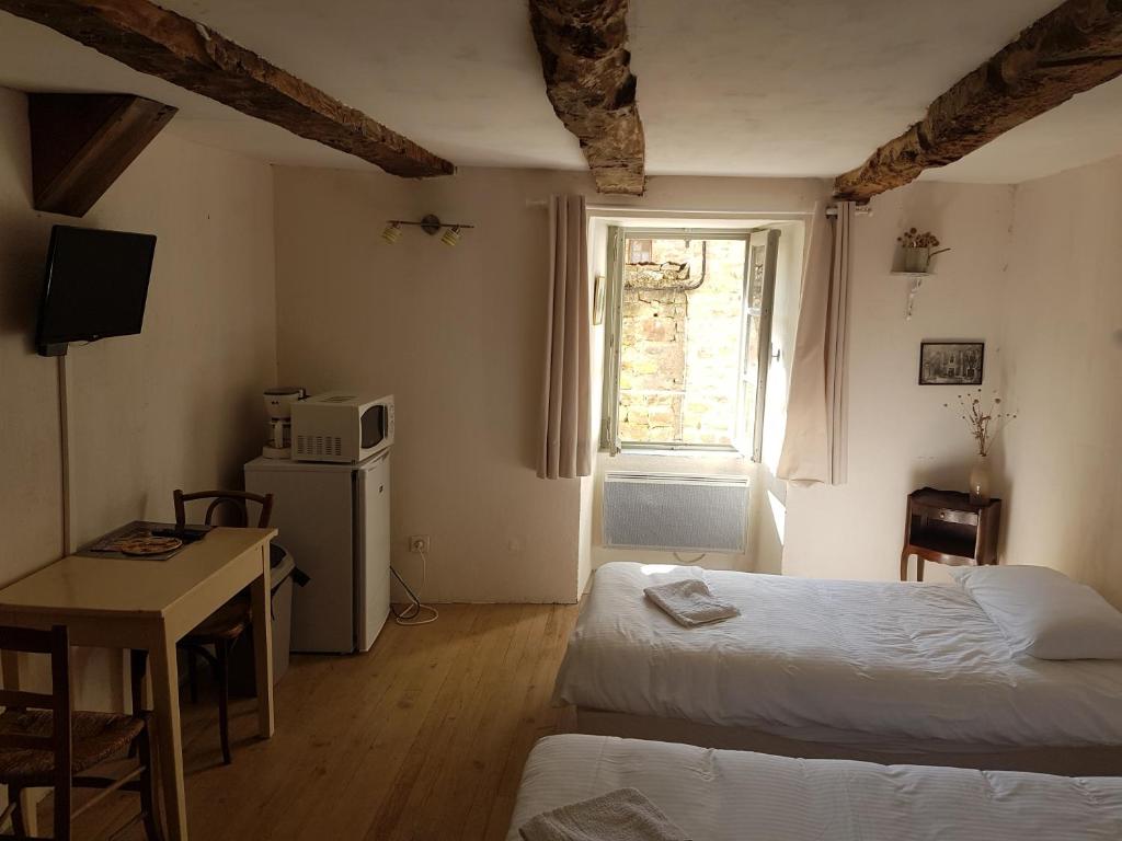 1 Schlafzimmer mit 2 Betten, einem Tisch und einem Fenster in der Unterkunft La maison d'Angèle in Sainte-Eulalie-du-Cernon