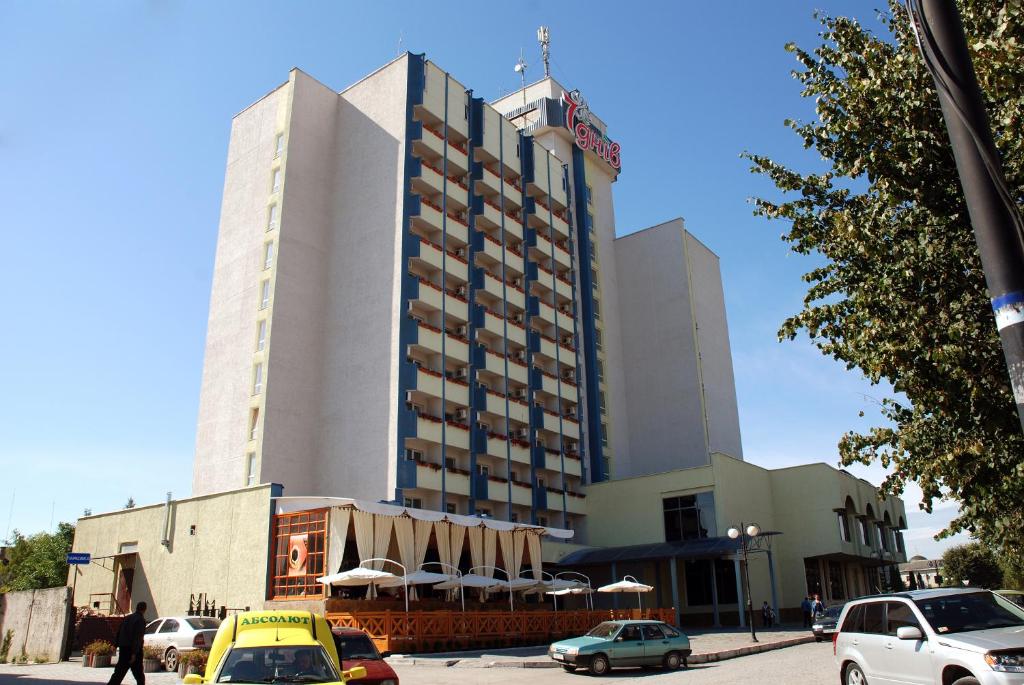 カームヤネツィ・ポジーリシクィイにある7 Days Hotel Kamyanets-Podilskyiの車が目の前に停まった大きな建物