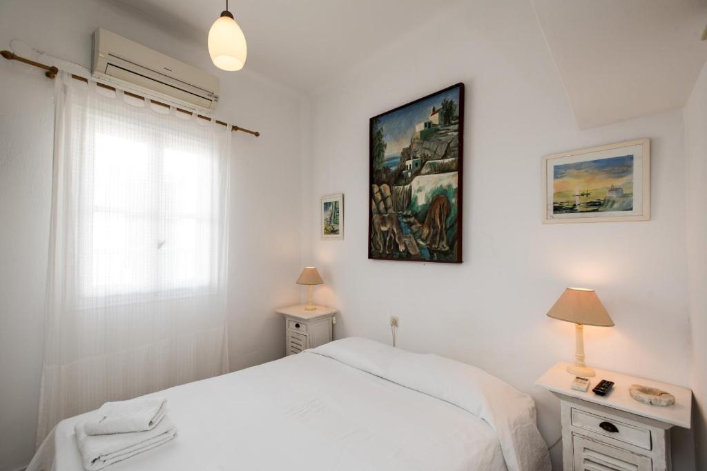 a white bedroom with a bed and a window at Hotel Delphines in Mýkonos City
