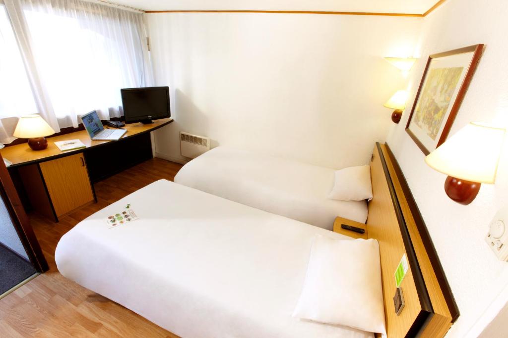 a hotel room with two beds and a desk at Campanile Dunkerque Est - Armbouts-Cappel in Armbouts-Cappel