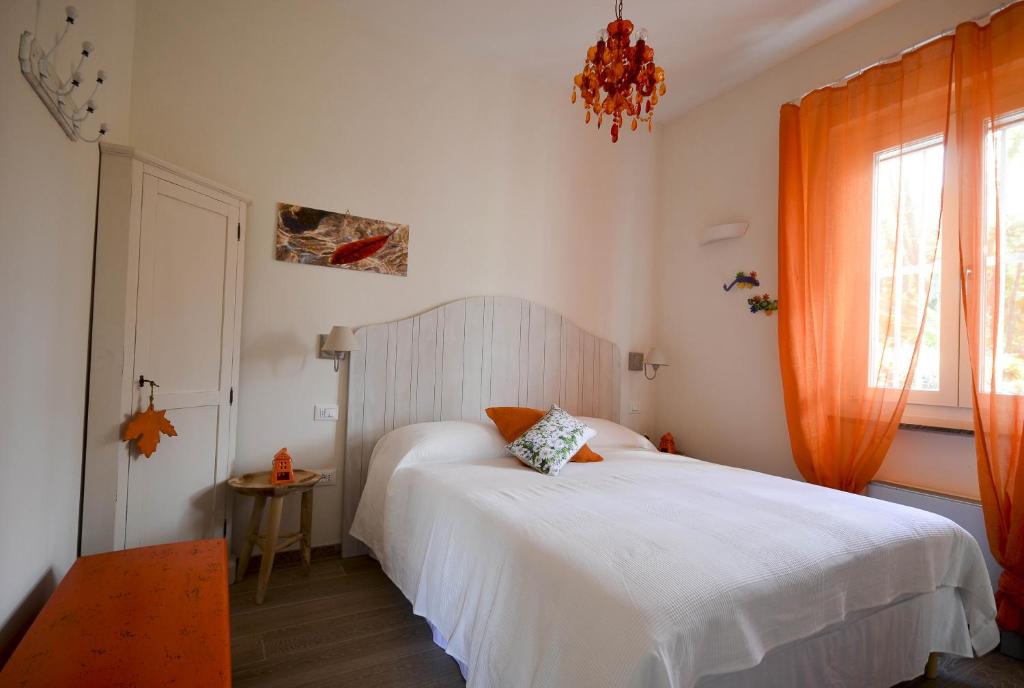 una camera con un letto bianco con una tenda arancione di Villa Porto sul Magra ad Ameglia
