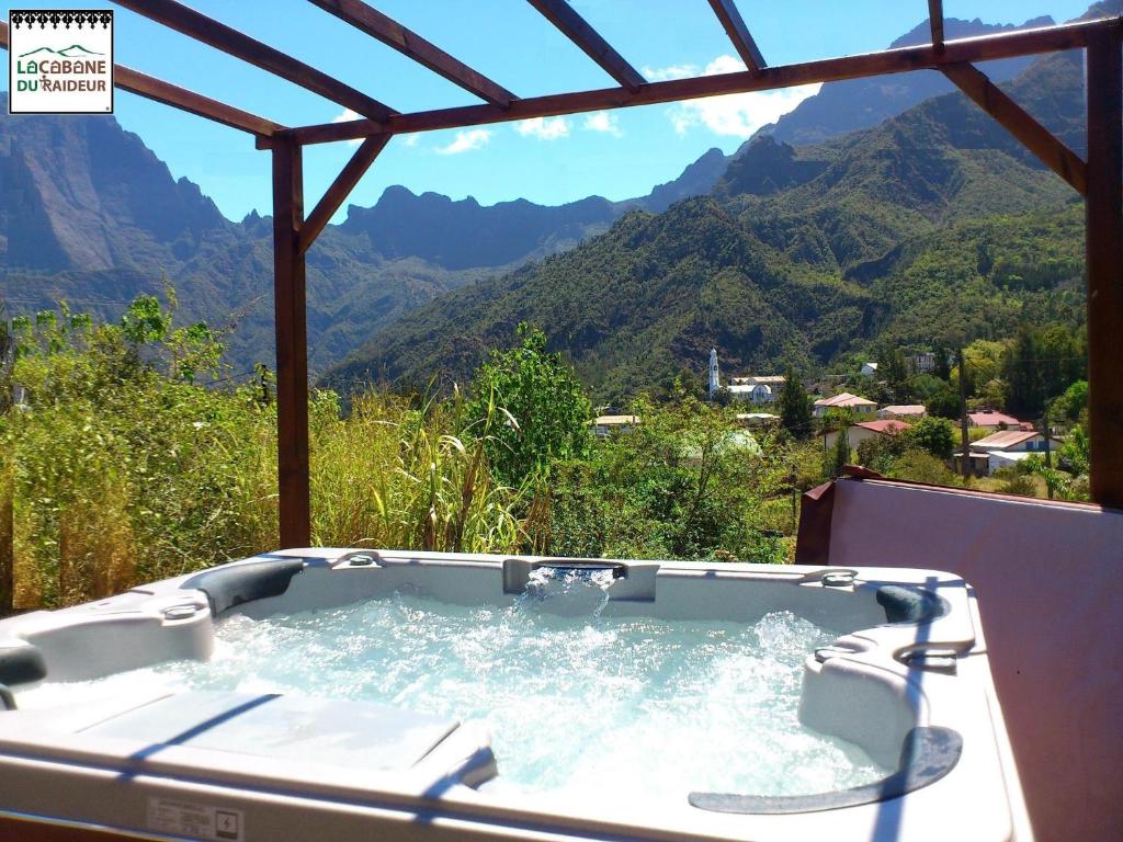 a hot tub with a view of the mountains at La Cabane du Raideur in Cilaos
