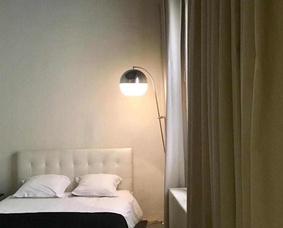 - une chambre avec un lit blanc et une lampe dans l'établissement Palais des Rois d'Aragon, à Montpellier