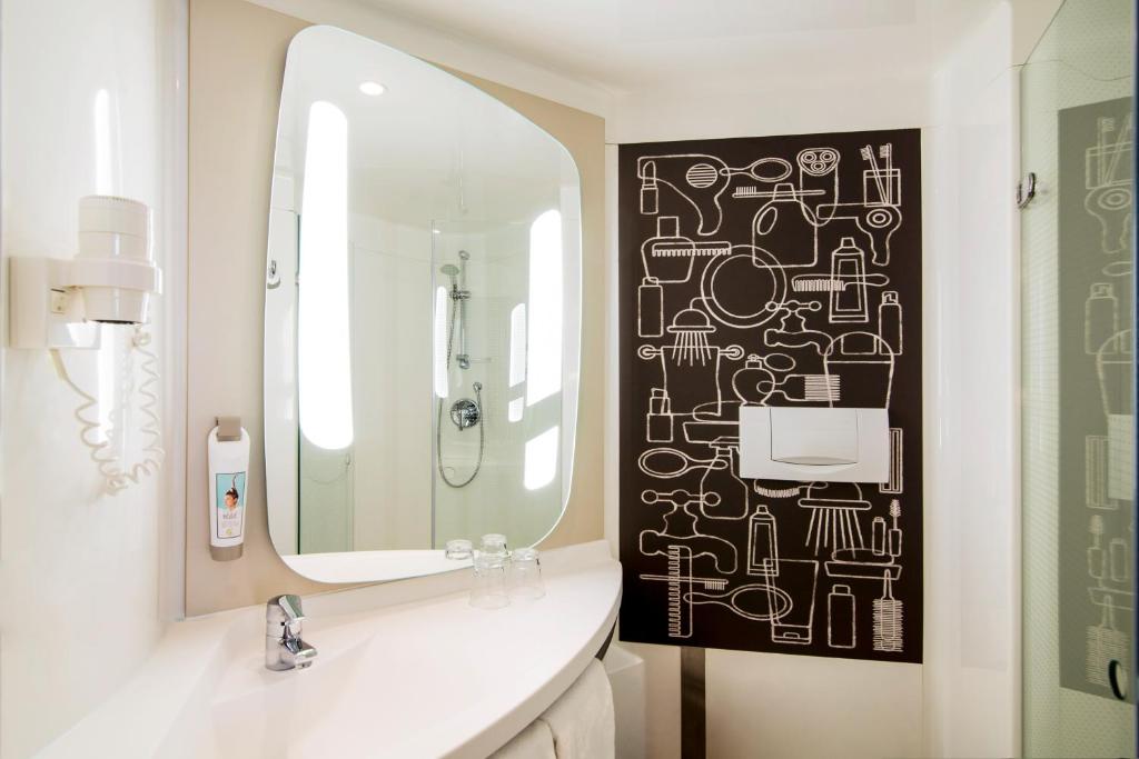 a bathroom with a mirror and a white sink at Ibis Schiphol Amsterdam Airport in Badhoevedorp
