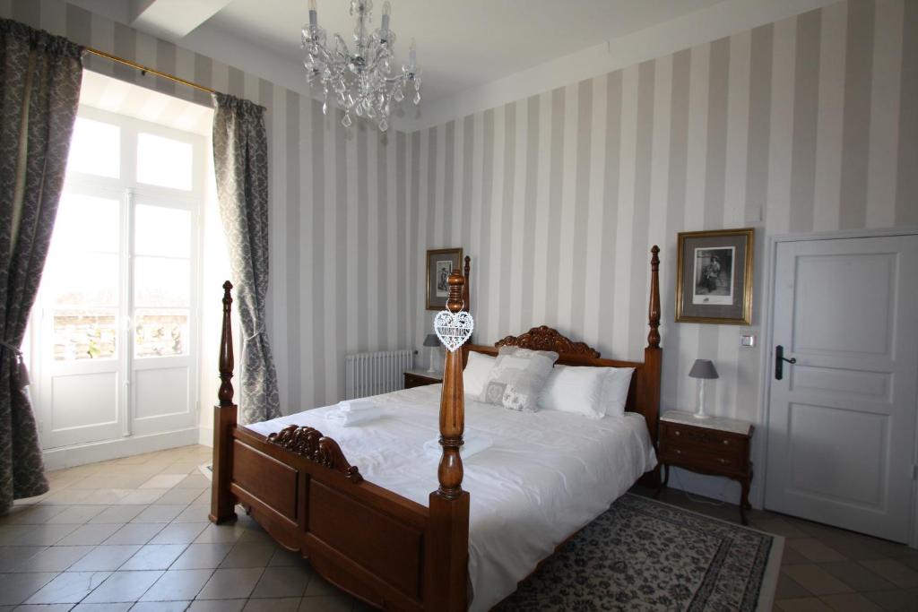 um quarto com uma cama grande e um lustre em Maison de Mallast em Montolieu