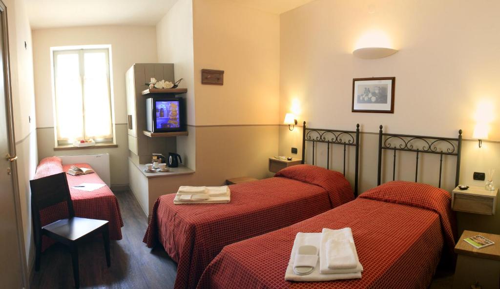 um quarto de hotel com duas camas e uma televisão em Albergo Benito em Norcia