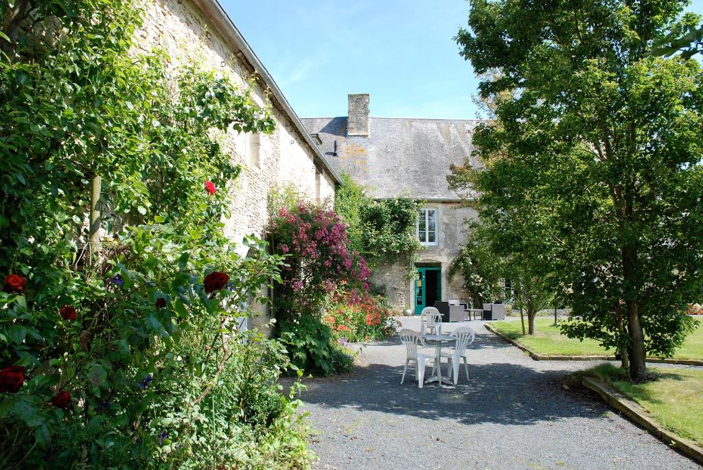 een tuin met een tafel en stoelen voor een huis bij Chambres d'Hôtes Les Piéris in Grandcamp-Maisy
