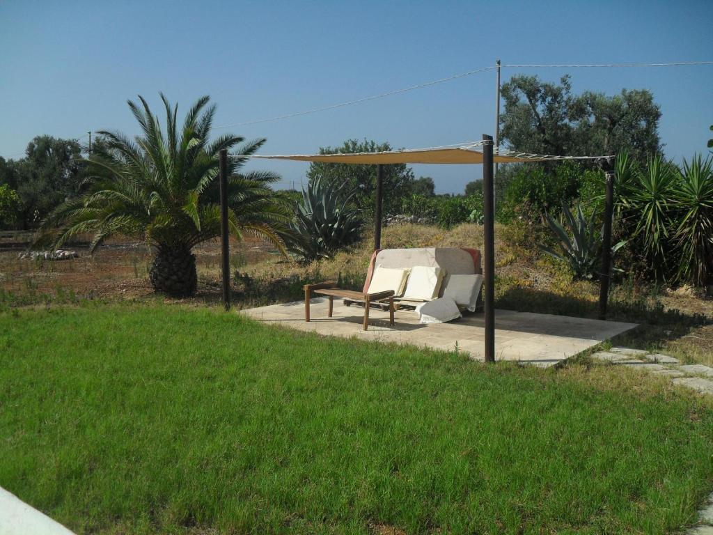 a chair and a bench under a gazebo at Case d'Artista in Savelletri di Fasano