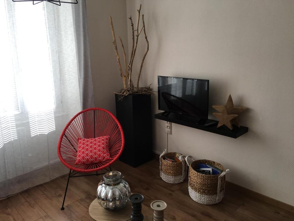 - un salon avec une chaise rouge et une télévision dans l'établissement Appartement Colmar Petite Venise, à Colmar