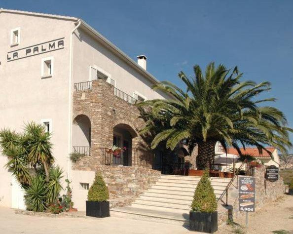 un edificio con una palmera delante de él en Hôtel la Palma, en Patrimonio