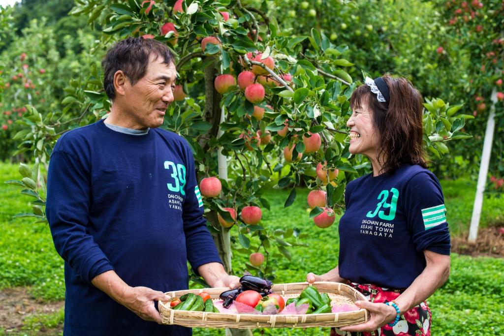un hombre y una mujer sosteniendo una cesta de manzanas en Daichan Farm Guest House, en Asahi-machi