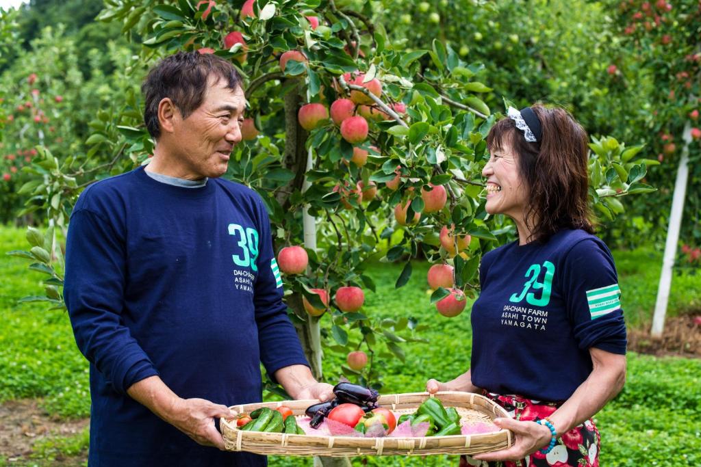 Un uomo e una donna che tengono in mano un cesto di mele di Daichan Farm Guest House a Asahi-machi