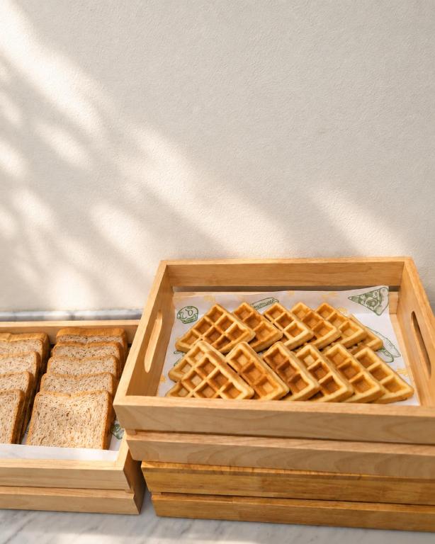 A breakfast display of waffles and sliced bread in wooden trays.