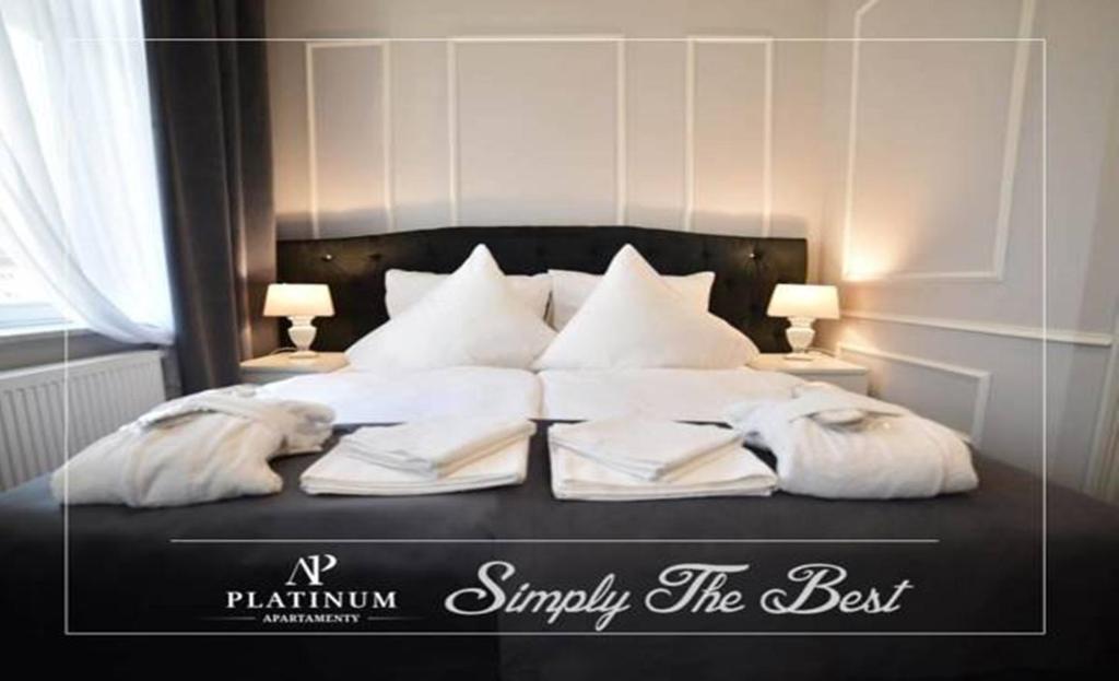 a bed with a white comforter and pillows at Aparthotel Platinum Apartamenty in Inowrocław