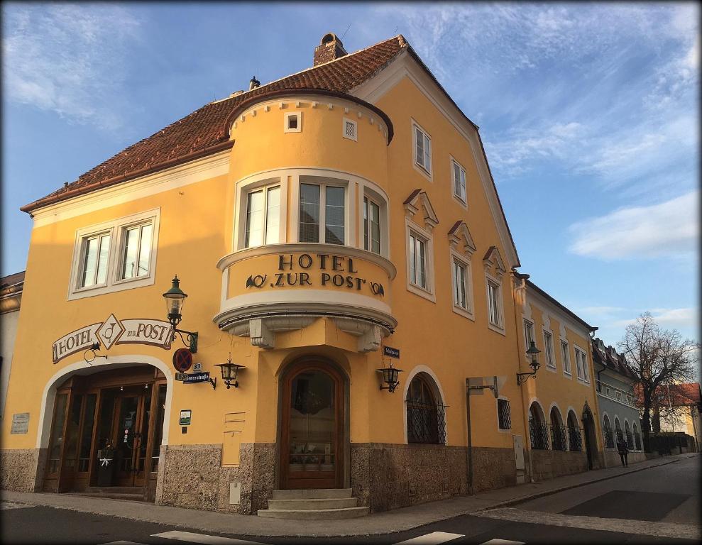 ein gelbes Gebäude mit einem Hotel in einer Straße in der Unterkunft Hotel zur Post in Gumpoldskirchen