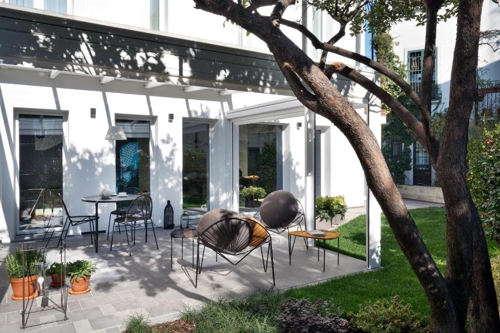 een patio met stoelen en tafels en een boom bij Conti Guest House in Milaan