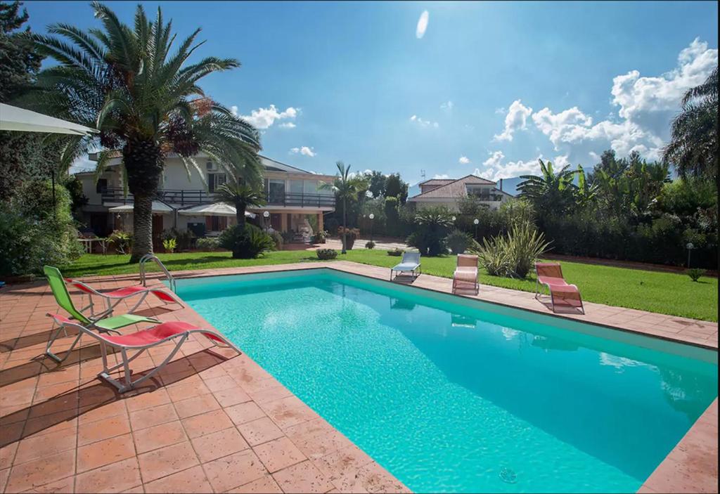 ein Pool mit zwei Gartenstühlen neben einem Haus in der Unterkunft Piccola Oasi in Mondello