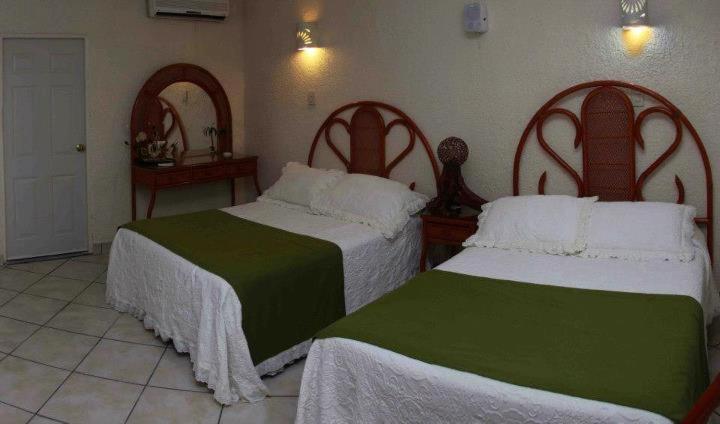 イスタパにあるVilla Cupatitzioのベッドルーム1室(ベッド2台、白と緑のシーツ付)