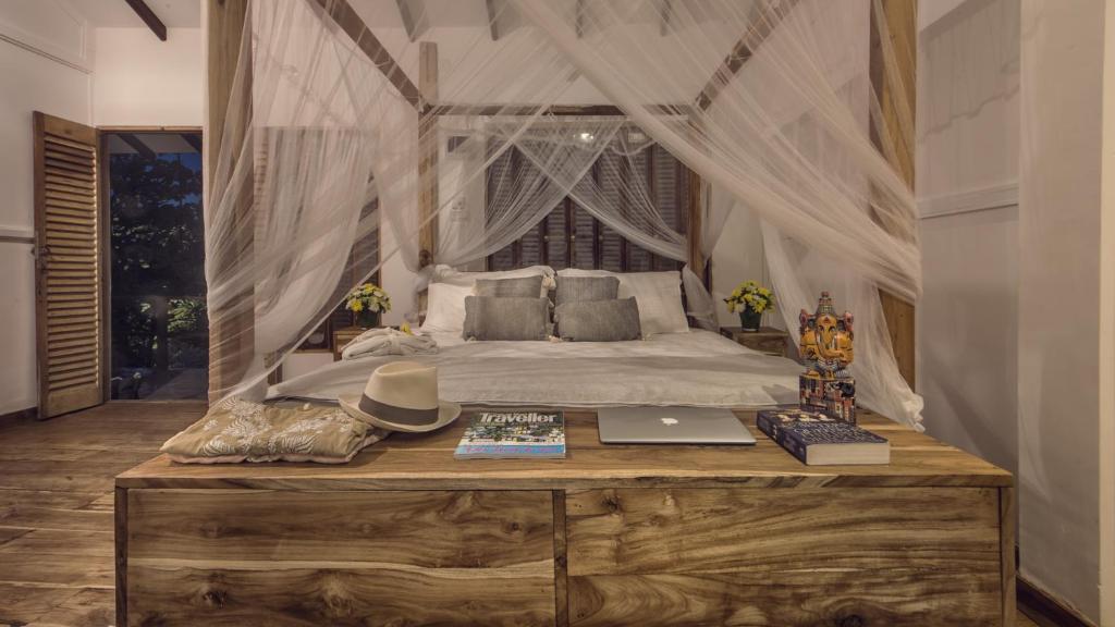 a bedroom with a canopy bed with a laptop on a table at C Beyond Nilaveli in Nilaveli