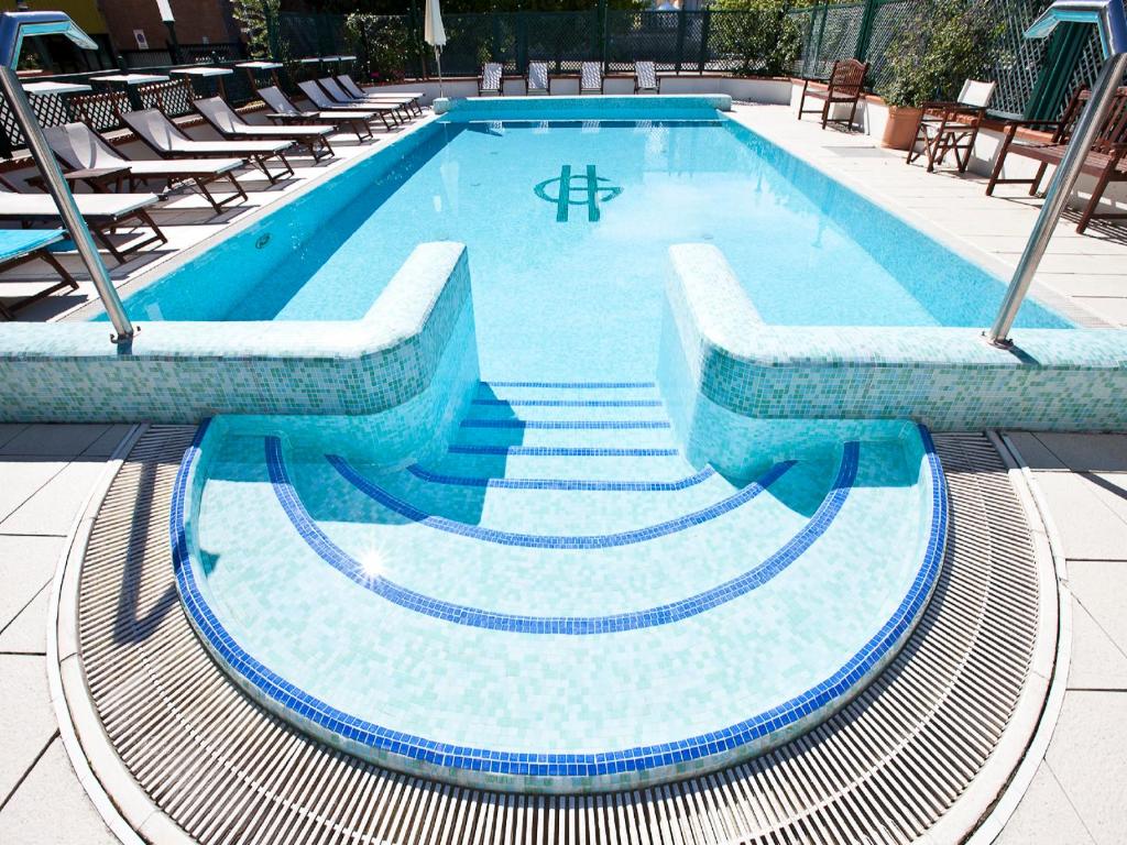 a swimming pool with stairs and chairs around it at Hotel Gaby in Rimini
