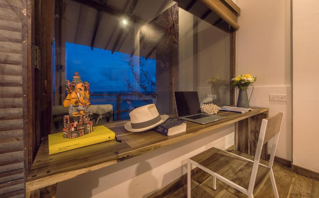 a desk with a hat and a laptop on it at C Beyond Nilaveli in Nilaveli