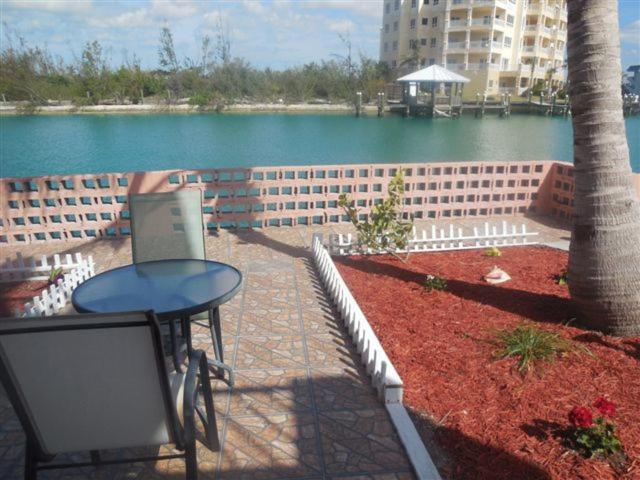 eine Terrasse mit einem Tisch neben einem Wasserkörper in der Unterkunft Dundee Bay Villas in Freeport