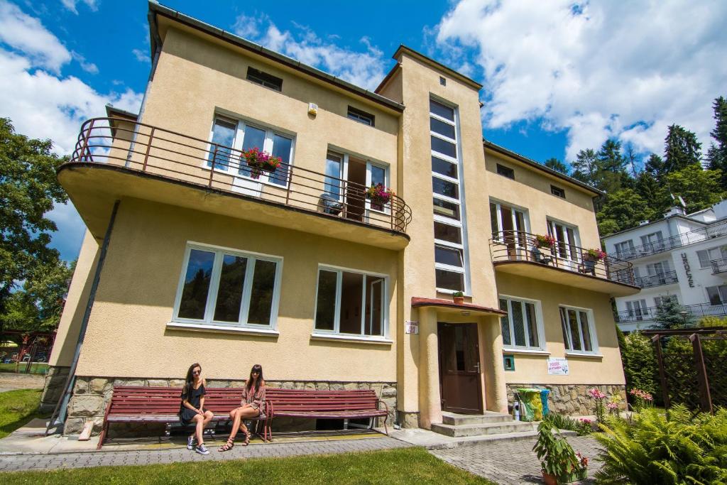 two women sitting on a bench in front of a building at Bukowianka in Muszyna