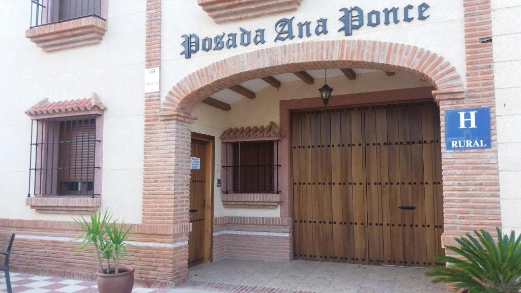 un edificio con una porta di legno di fronte di Posada Ana Ponce a Sierra de Yeguas