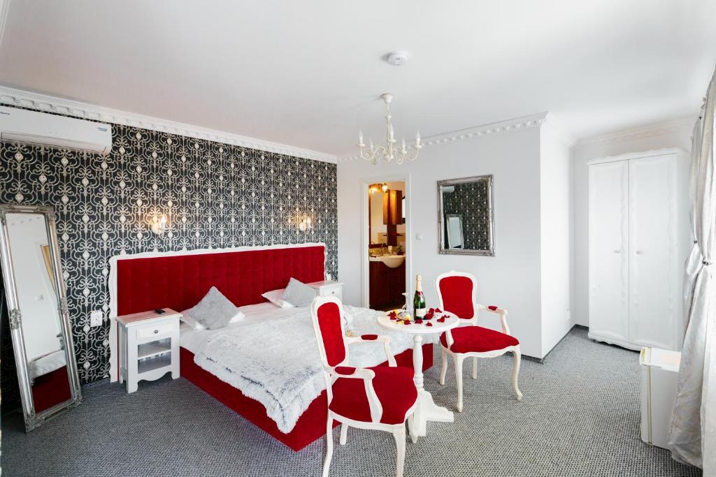 una camera con letto rosso e tavolo e sedie di Pensiunea Avy a Haţeg