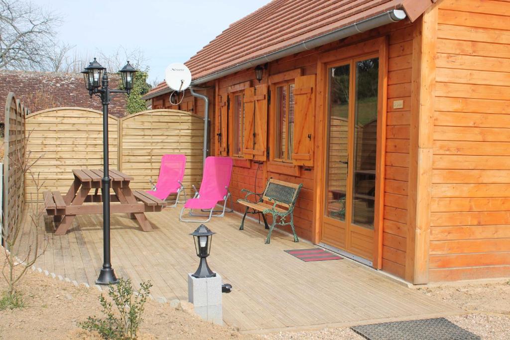 a wooden cabin with pink chairs and a table at Les Cottages de Charme in Saint-Aignan