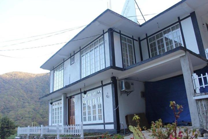 una casa azul y blanca con montañas en el fondo en Believe Inn, en Nuwara Eliya