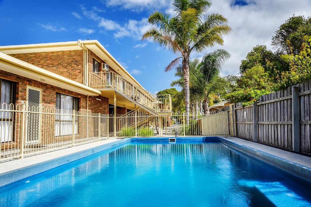 una piscina frente a una casa con una valla en Allambi Holiday Apartments, en Lakes Entrance