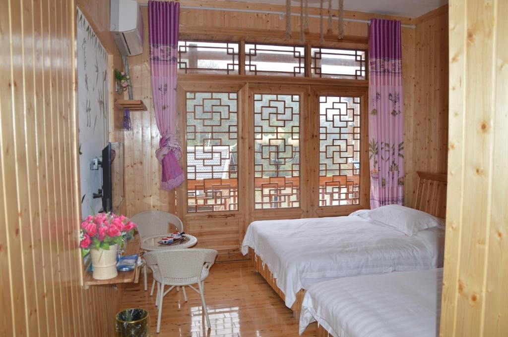 a bedroom with two beds and a table and a window at Yangjiajie Inn in Zhangjiajie