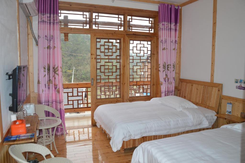 a bedroom with two beds and a window with purple curtains at Yangjiajie Inn in Zhangjiajie
