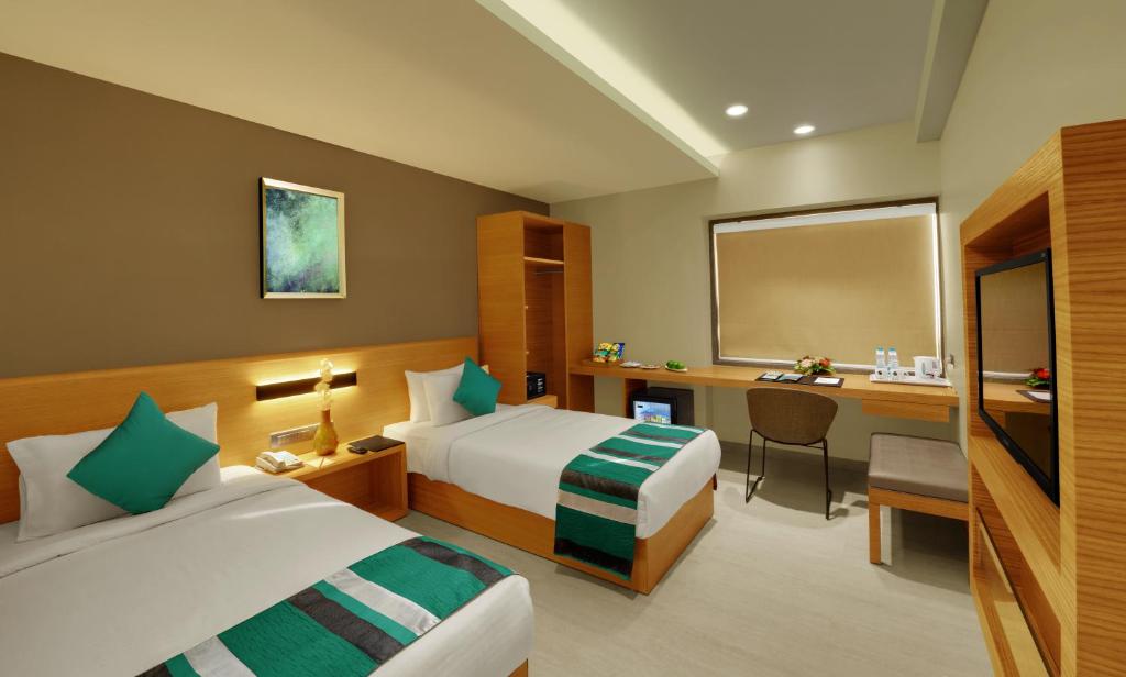 a hotel room with two beds and a desk at Click Hotel Bhuj in Bhuj