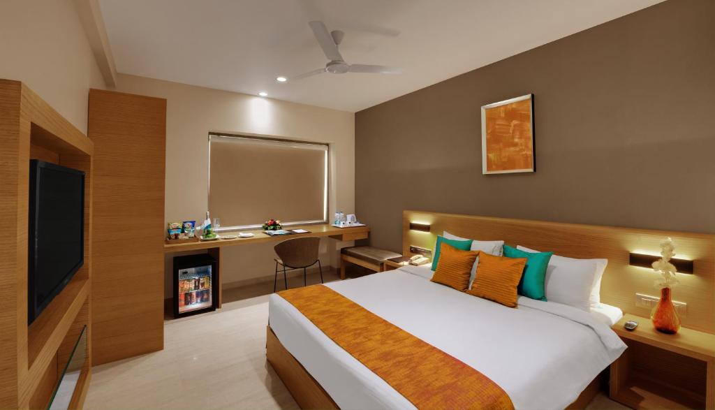 a bedroom with a bed and a desk and a television at Click Hotel Bhuj in Bhuj