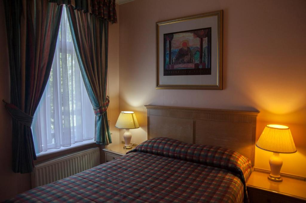 a bedroom with a bed and two lamps and a window at Her Majesty Hotel in London